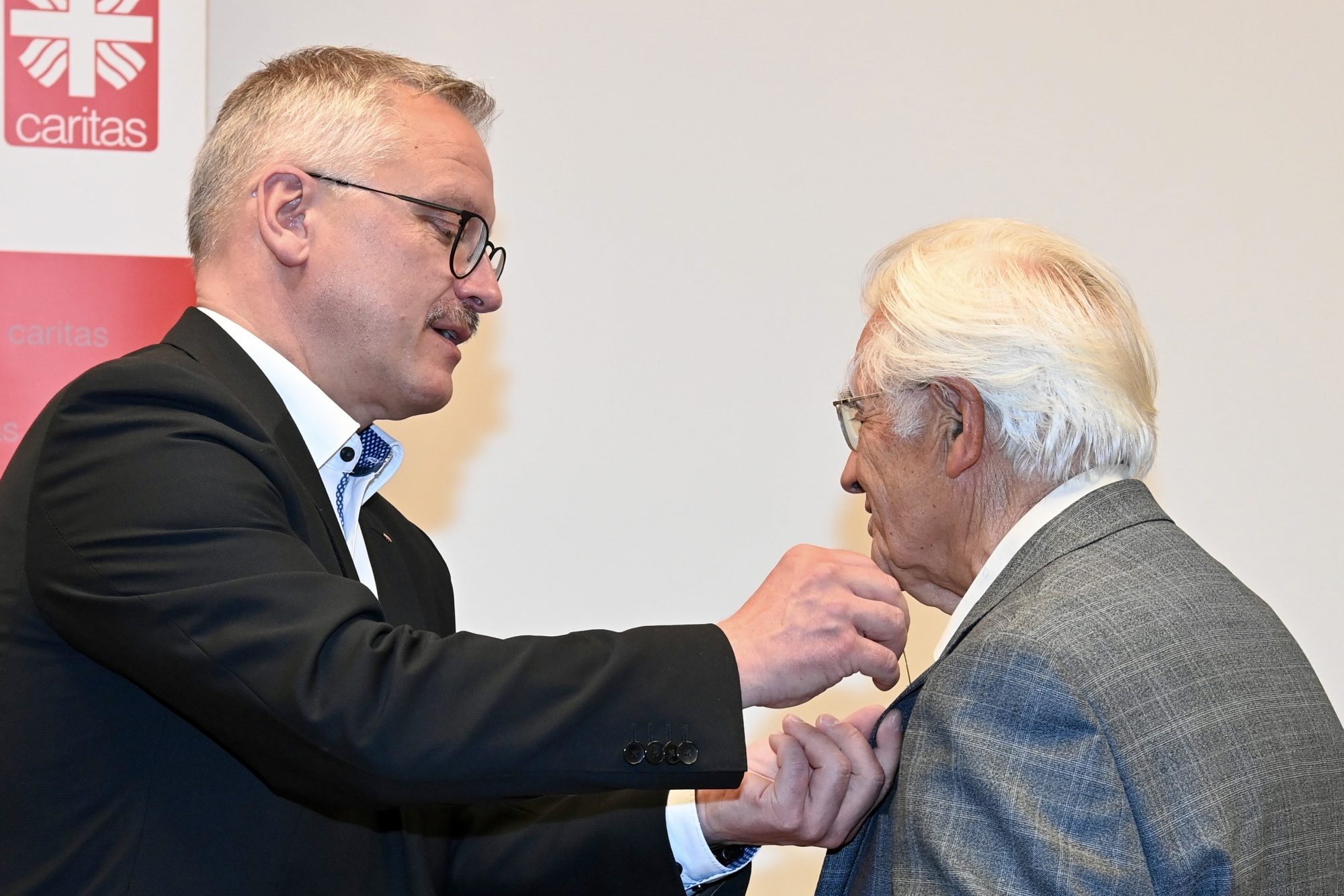 Person steckt einer anderen etwas an den Kragen