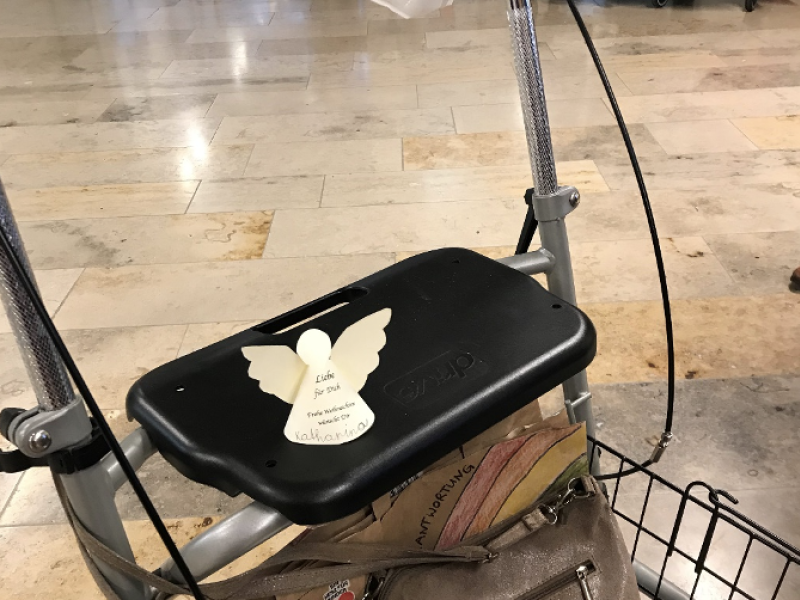 Ein Rollator steht in einem Flur oder Aufenthaltsraum. Der Raum wirkt hell und funktional.