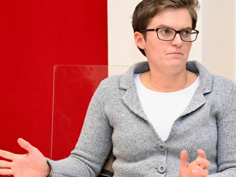 Eine Person vor rotem Hintergrund gestikuliert w&auml;hrend eines Gespr&auml;chs.