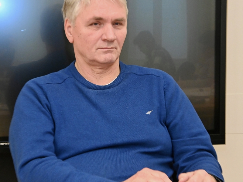 Ein Mann mit hellen Haaren sitzt in einem Raum und blickt seitlich.