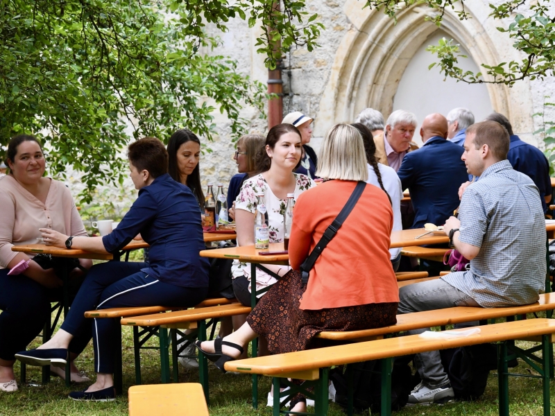 Personen im Garten an Bierb&auml;nken