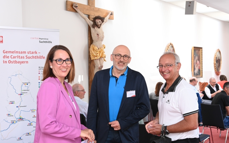 Drei Personen vor Kreuz