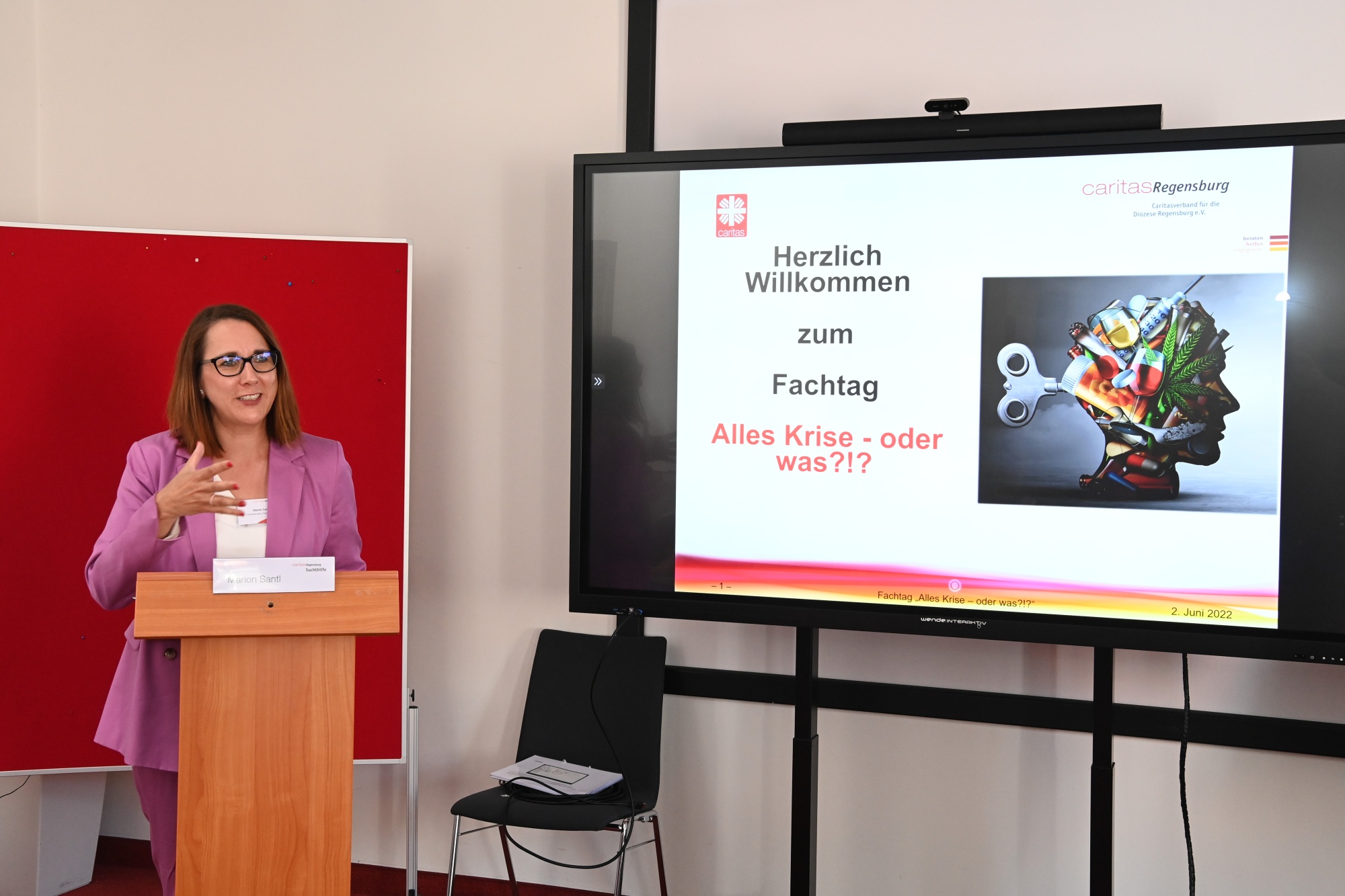 Rednerin vor Fernseher