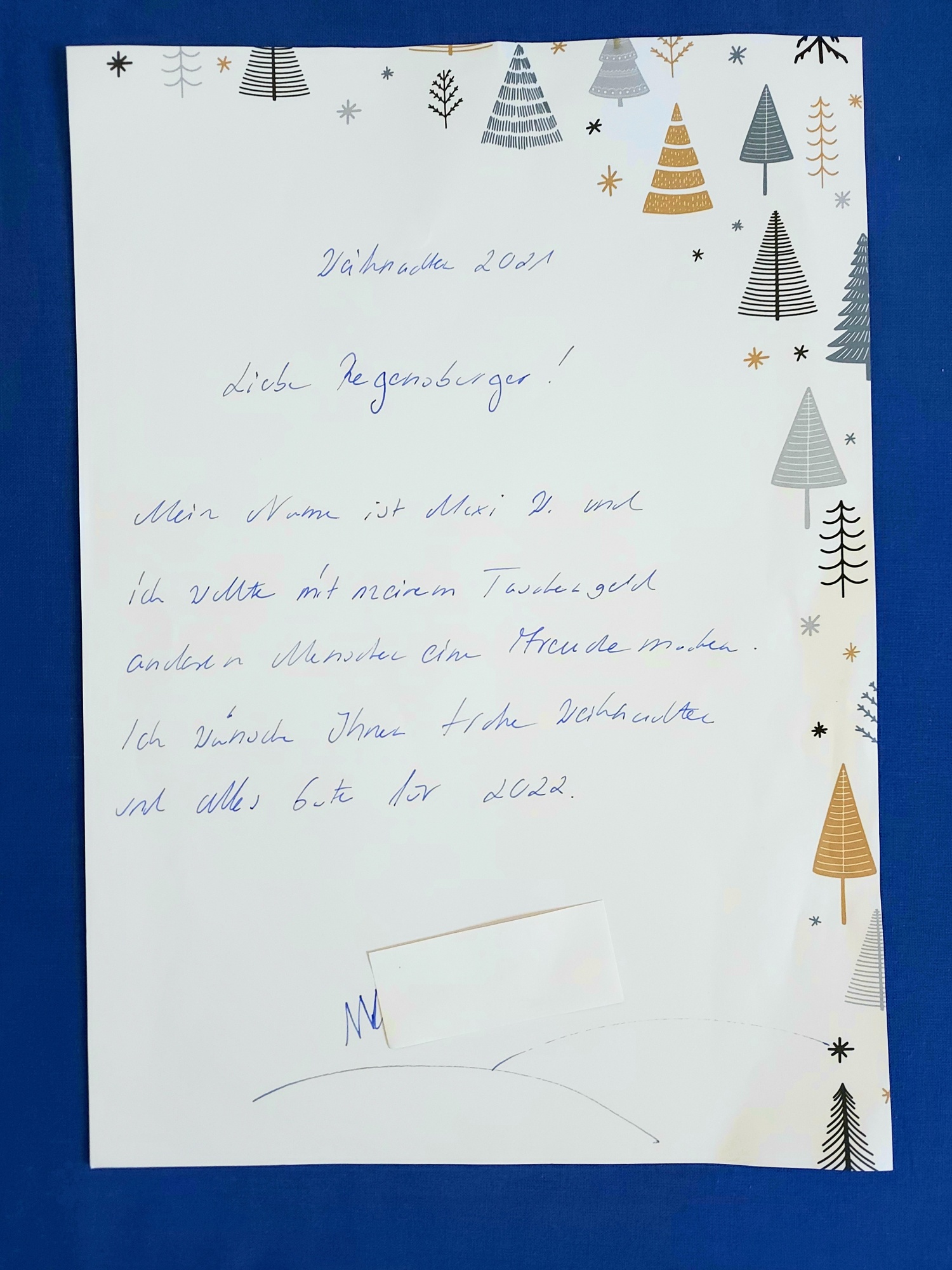 Ein Dokument oder Brief mit weihnachtlicher Gestaltung liegt flach ausgebreitet.