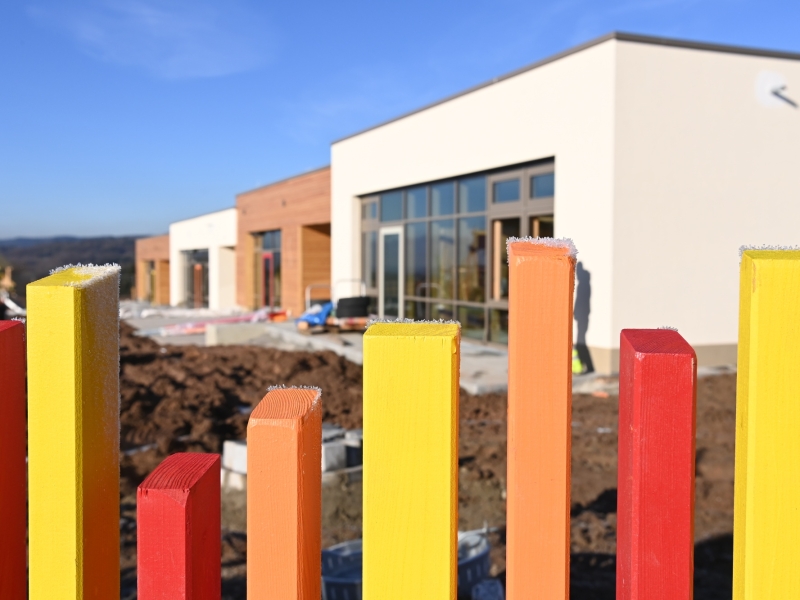 Flacher Neubau mit gro&szlig;en Fenstern und Holzverkleidung auf einem Baustellengel&auml;nde in l&auml;ndlicher Umgebung