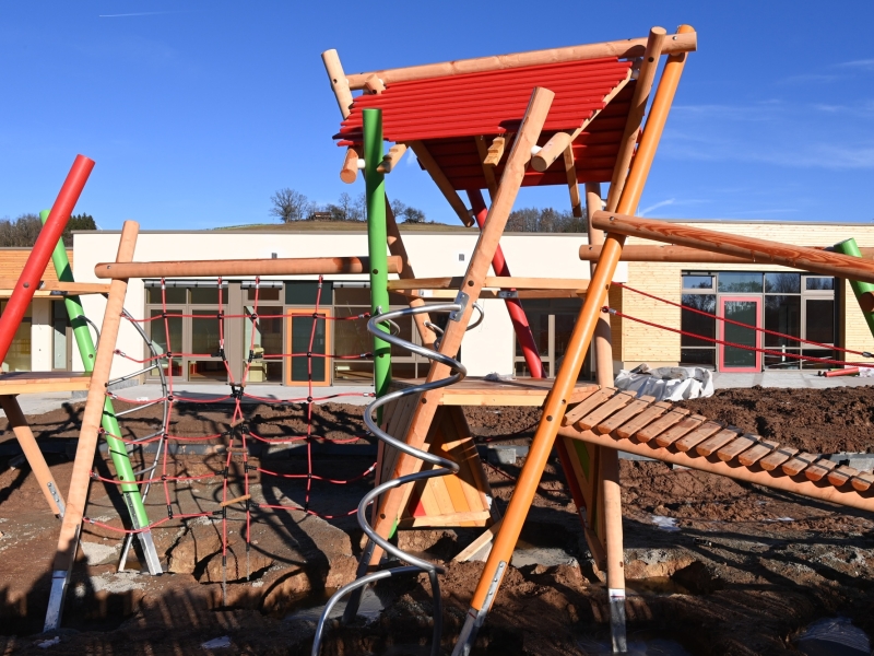Flacher Neubau mit gro&szlig;en Fenstern und Holzverkleidung auf einem Baustellengel&auml;nde in l&auml;ndlicher Umgebung